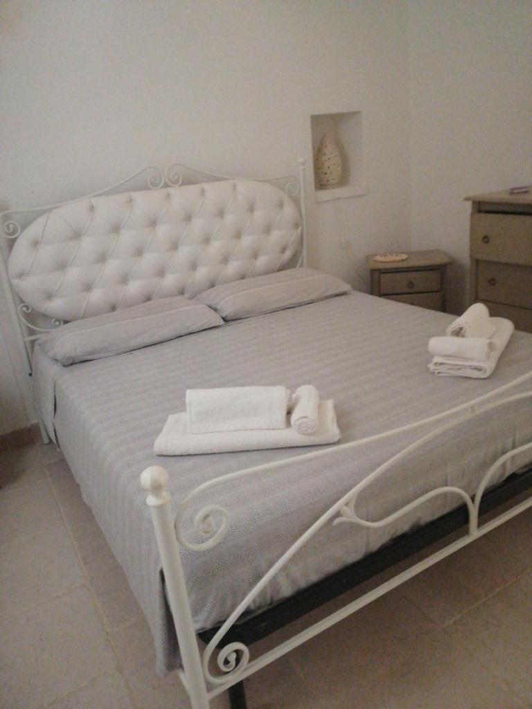 une chambre avec un lit blanc avec des serviettes dessus dans l'établissement Trulli LENUCCIA villa, à Ceglie Messapica
