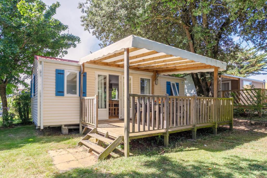 une petite maison avec une terrasse couverte et une terrasse en bois dans l'établissement Camping Ushuaïa Villages Le Parc de la Grève, à LʼAiguillon-sur-Vie