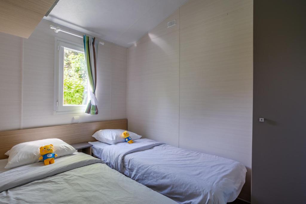 deux lits dans une chambre avec une fenêtre dans l'établissement Camping Ushuaïa Villages Le Parc de la Grève, à LʼAiguillon-sur-Vie 16 autres photos