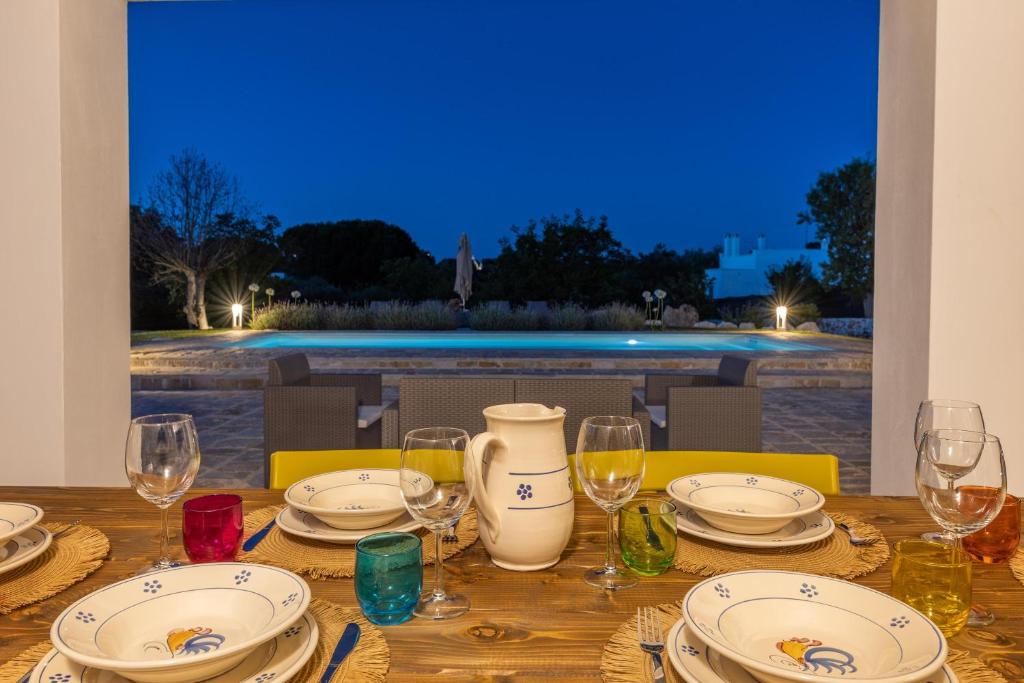une table en bois avec des assiettes et des verres à vin dessus dans l'établissement Trullo Adea, à Ceglie Messapica