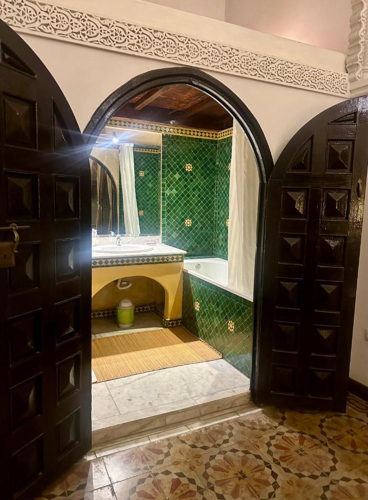 La salle de bains est pourvue d'une baignoire, d'une douche et d'une porte ouverte. dans l'établissement Riad A La Belle Etoile, à Sale