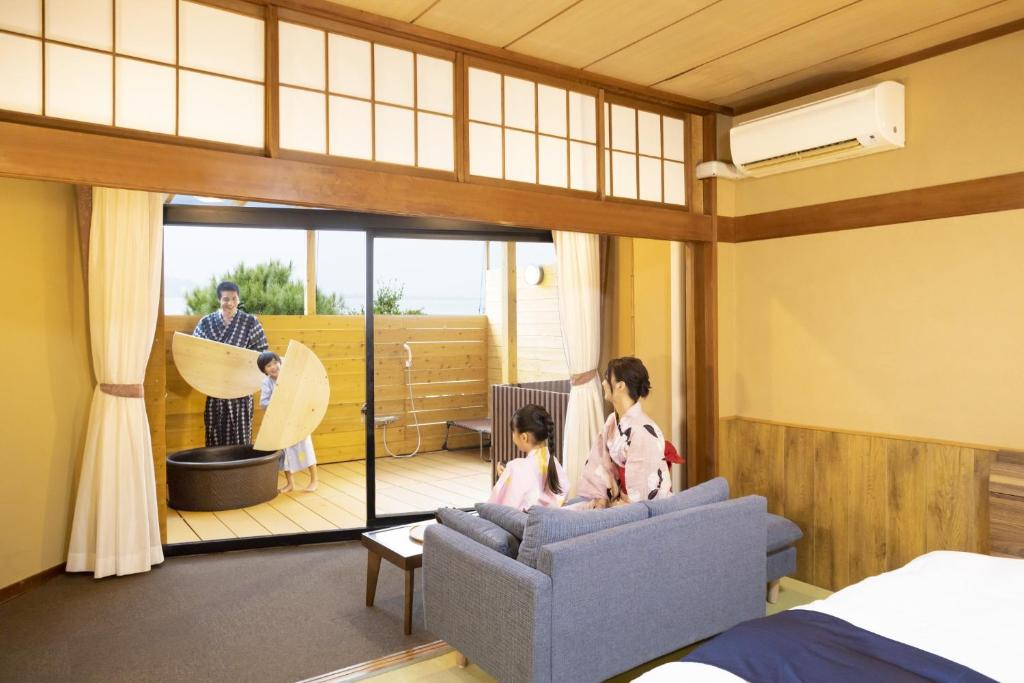 un homme et deux enfants debout dans un salon dans l'établissement Ooedo Onsen Monogatari Premium Kaga Maruya, à Kaga