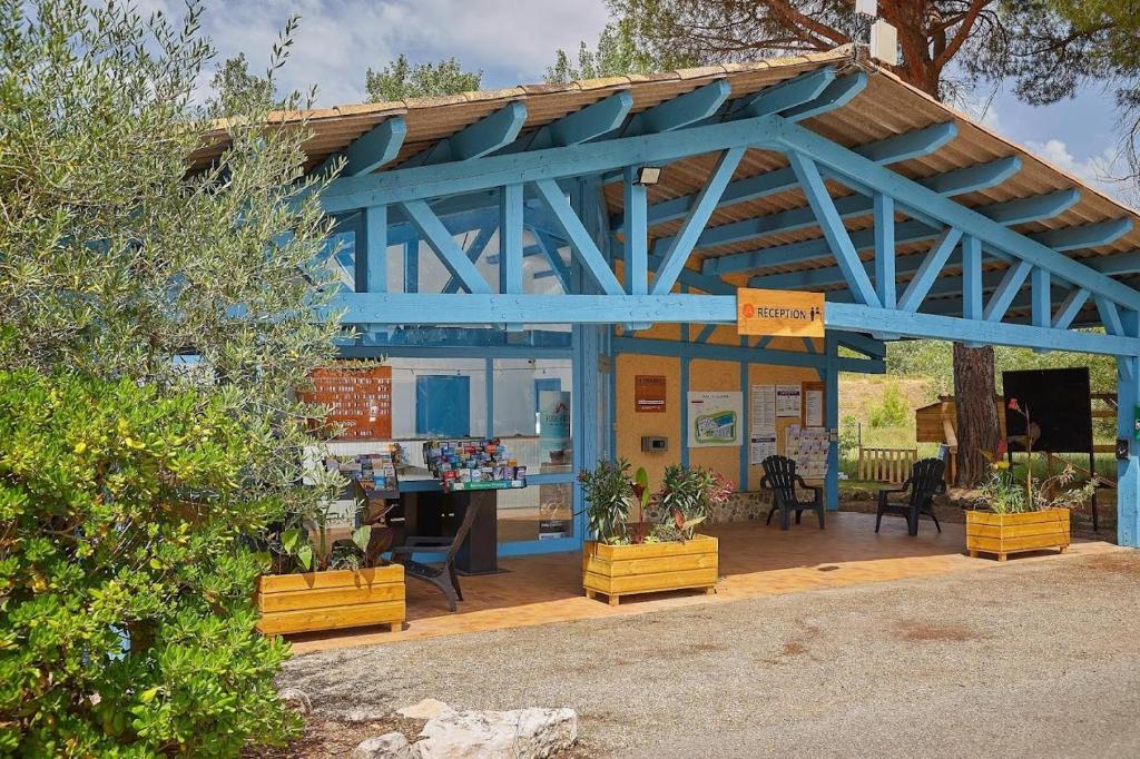 un bâtiment bleu avec un magasin avec des plantes dans l'établissement mobil-home 43, à La Roque-dʼAnthéron