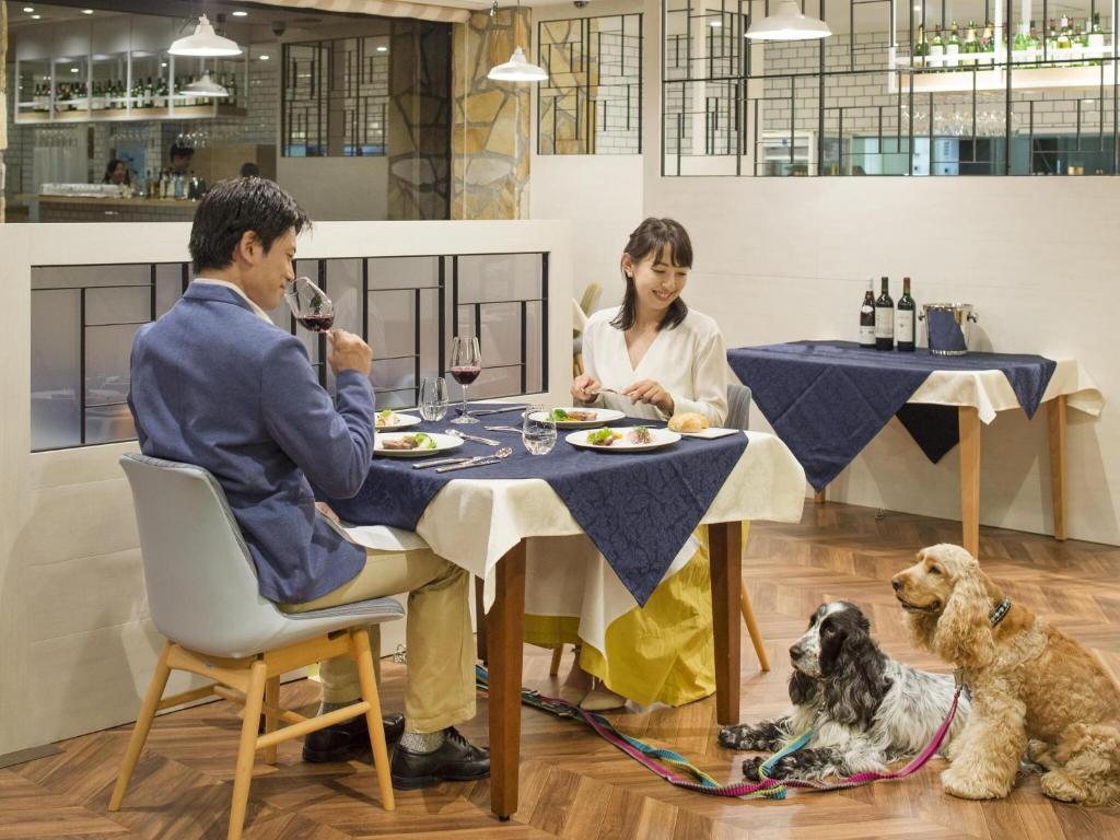 un homme et une femme assis à une table avec un chien dans l'établissement Wan's Resort Yamanakako, à Yamanakako