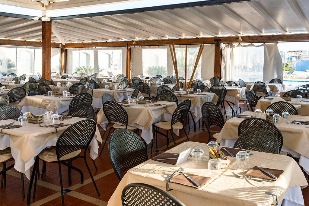 une salle à manger avec tables et chaises avec du linge blanc dans l'établissement Baia dei Mulini Resort & Spa, à Trapani