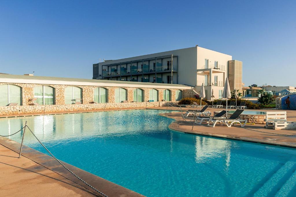 une grande piscine devant un immeuble dans l'établissement Baia dei Mulini Resort & Spa, à Trapani