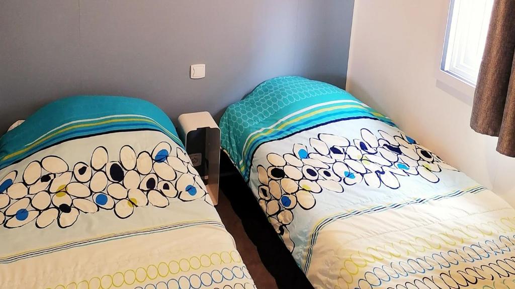 deux lits côte à côte dans une pièce dans l'établissement Camping Tikayan Félix de la Bastide, à Saint-Mitre-les-Remparts