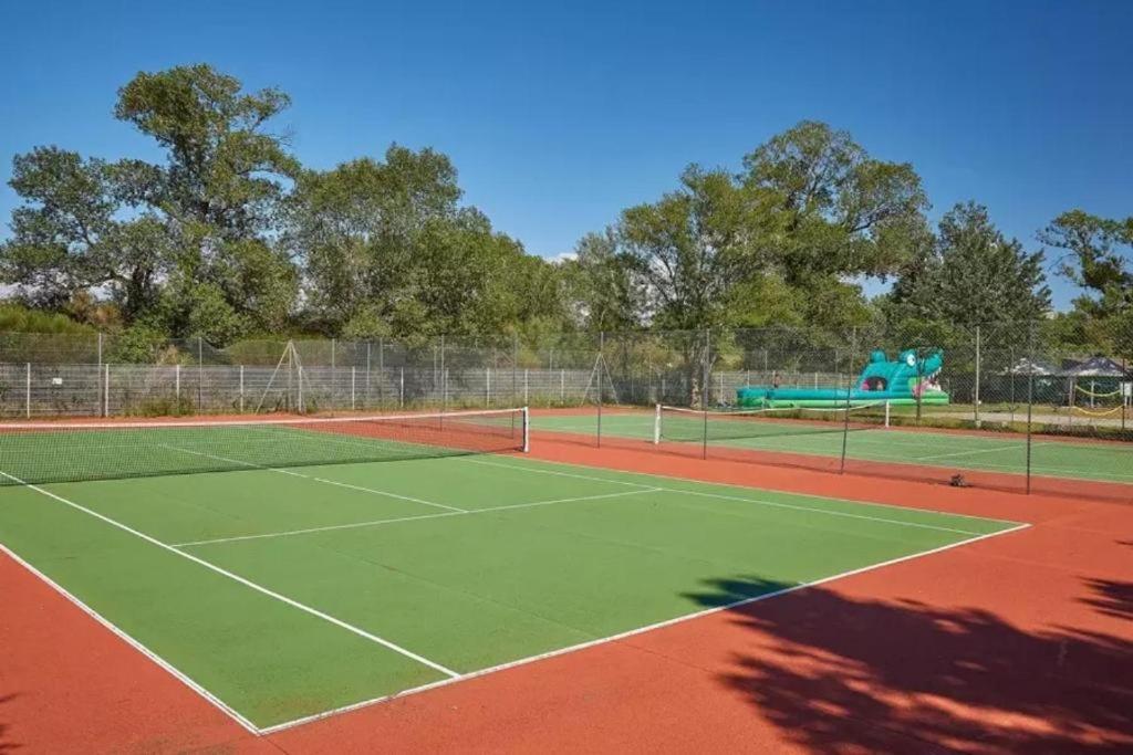 un court de tennis avec une aire de jeux en arrière-plan dans l'établissement MOBIL HOME LMNP GUIGON, à La Roque-dʼAnthéron