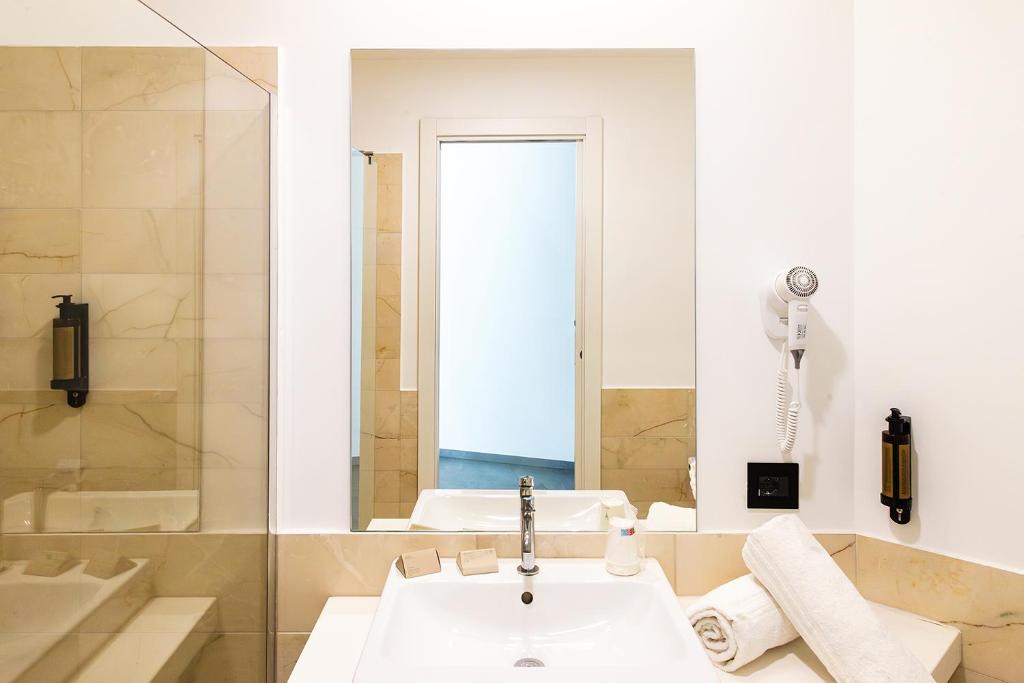 - une salle de bains blanche avec lavabo et téléphone dans l'établissement Baia dei Mulini Resort & Spa, à Trapani