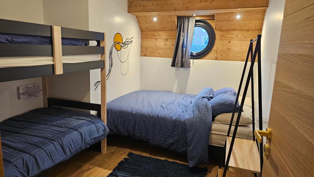 une chambre avec deux lits superposés et une fenêtre dans l'établissement La Péniche Mathurin - Gîte insolite sur l'eau, à Saint-Omer