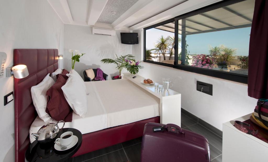 une chambre avec un lit blanc et une grande fenêtre dans l'établissement Hotel Gabriella, à Rimini