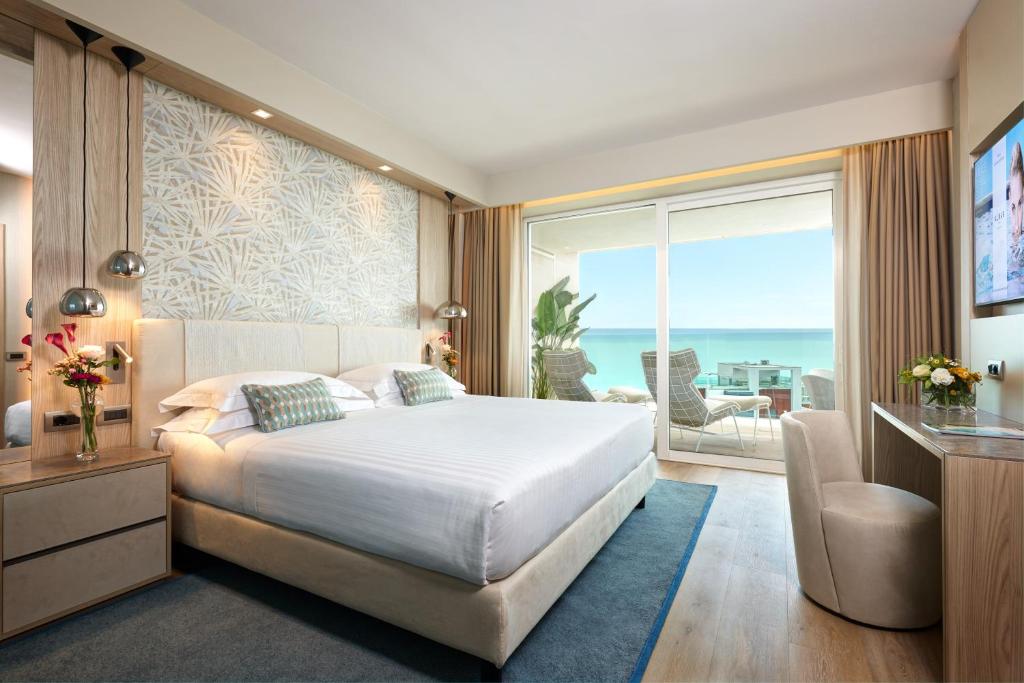 une chambre avec un grand lit et une grande fenêtre dans l'établissement Almar Lido Jesolo, à Lido di Jesolo