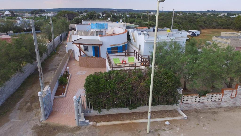 Elle offre une vue sur une maison blanche dotée d'un balcon. dans l'établissement Villa Azzurra con piscina e con vista mare fronte Spiaggia Specchiarica di San Pietro in Bevagna, à Torre Colimena