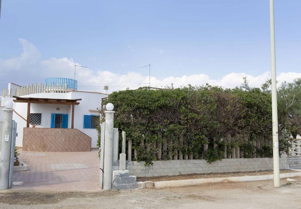 une clôture devant une maison avec un bâtiment dans l'établissement Villa Azzurra con piscina e con vista mare fronte Spiaggia Specchiarica di San Pietro in Bevagna, à Torre Colimena