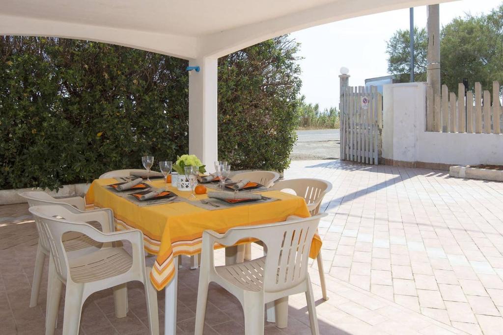 une table et des chaises avec un chiffon de table jaune sur la terrasse dans l'établissement Villa Azzurra con piscina e con vista mare fronte Spiaggia Specchiarica di San Pietro in Bevagna, à Torre Colimena 64 autres photos