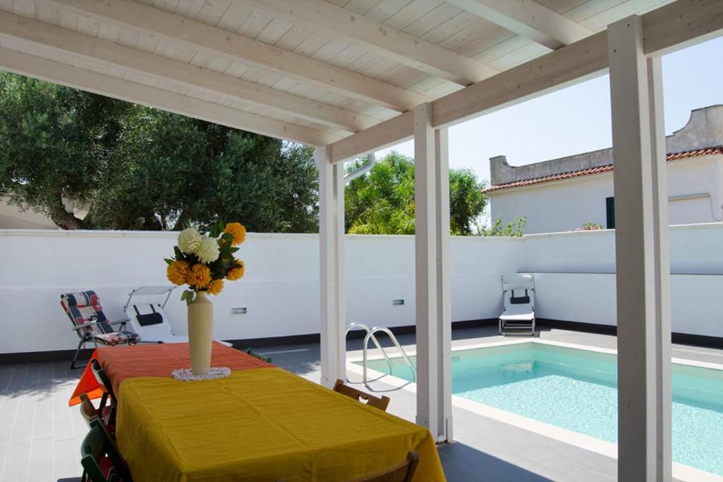 - une table avec un vase de fleurs sur la terrasse dans l'établissement Villa Maria con Piscina nel Boomerang Village a Torre Colimena, à Torre Colimena