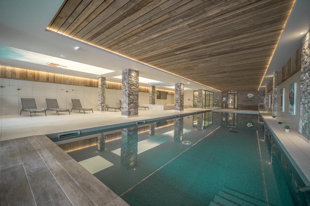 - une grande piscine dans un bâtiment doté d'un plafond en bois dans l'établissement Sky La Rosière by Alpapart, à La Rosière
