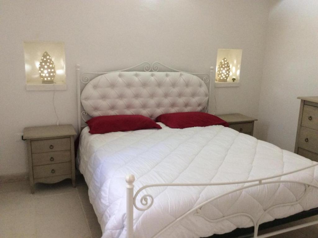 une chambre avec un grand lit blanc avec des oreillers rouges dans l'établissement Trulli LENUCCIA villa, à Ceglie Messapica 72 autres photos
