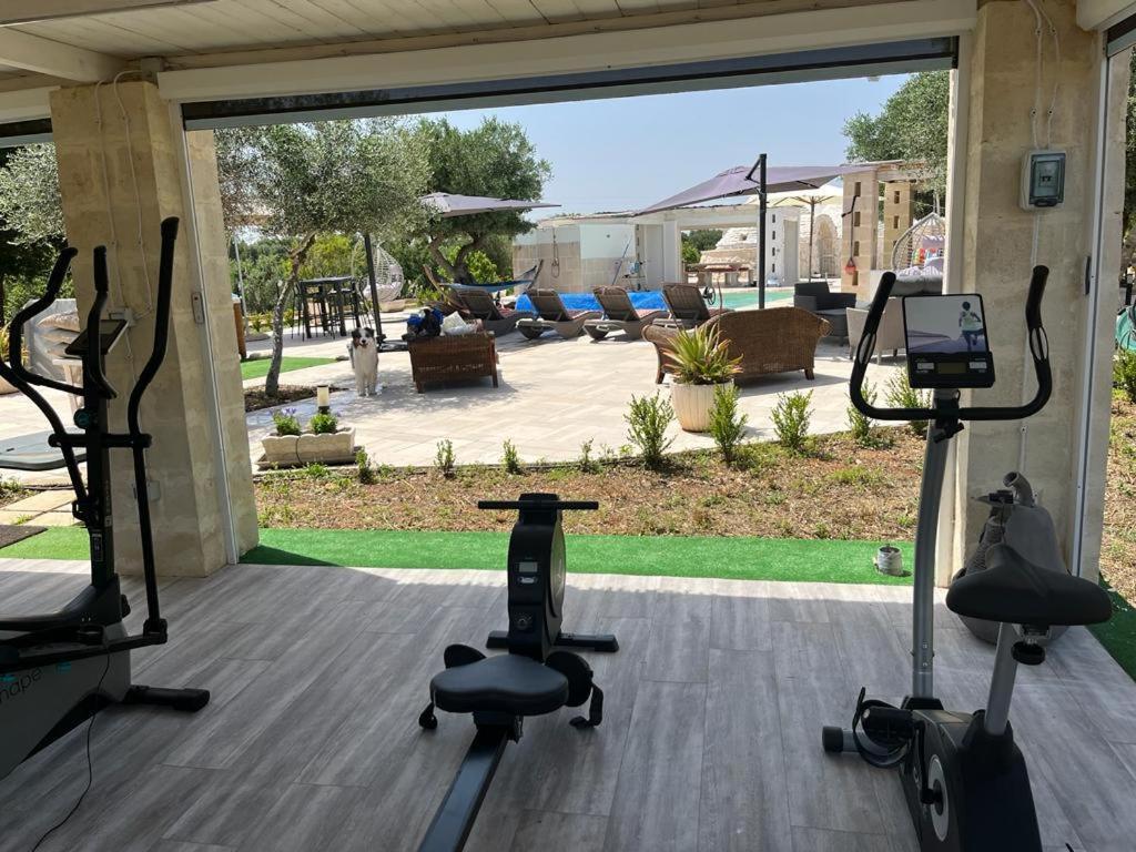 - une salle de sport avec deux vélos d'exercice devant une terrasse dans l'établissement Trulli LENUCCIA villa, à Ceglie Messapica