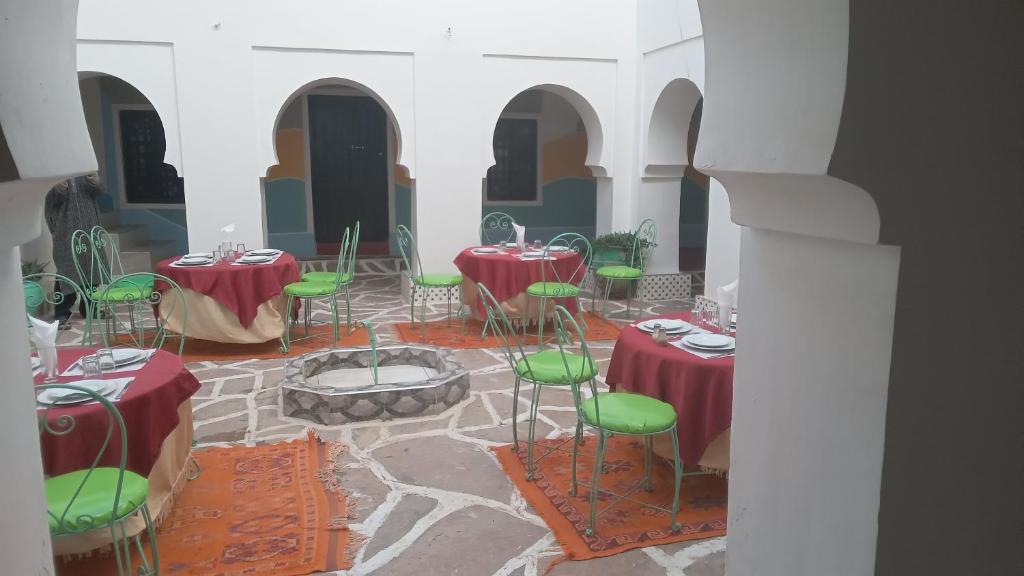 Cette chambre comprend des tables et des chaises rouges et vertes. dans l'établissement Riad Amodou, à Tinghir