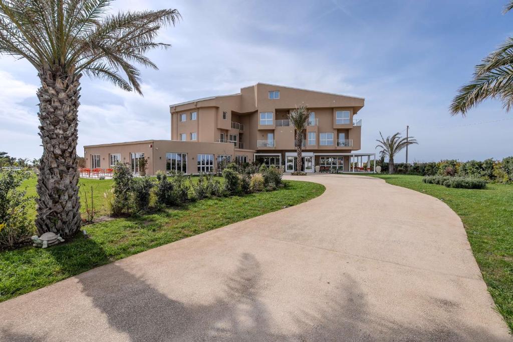 un bâtiment avec un palmier et une allée dans l'établissement Terradamari Resort & Spa Marina di Modica,Tapestry by Hilton, à Marina di Modica
