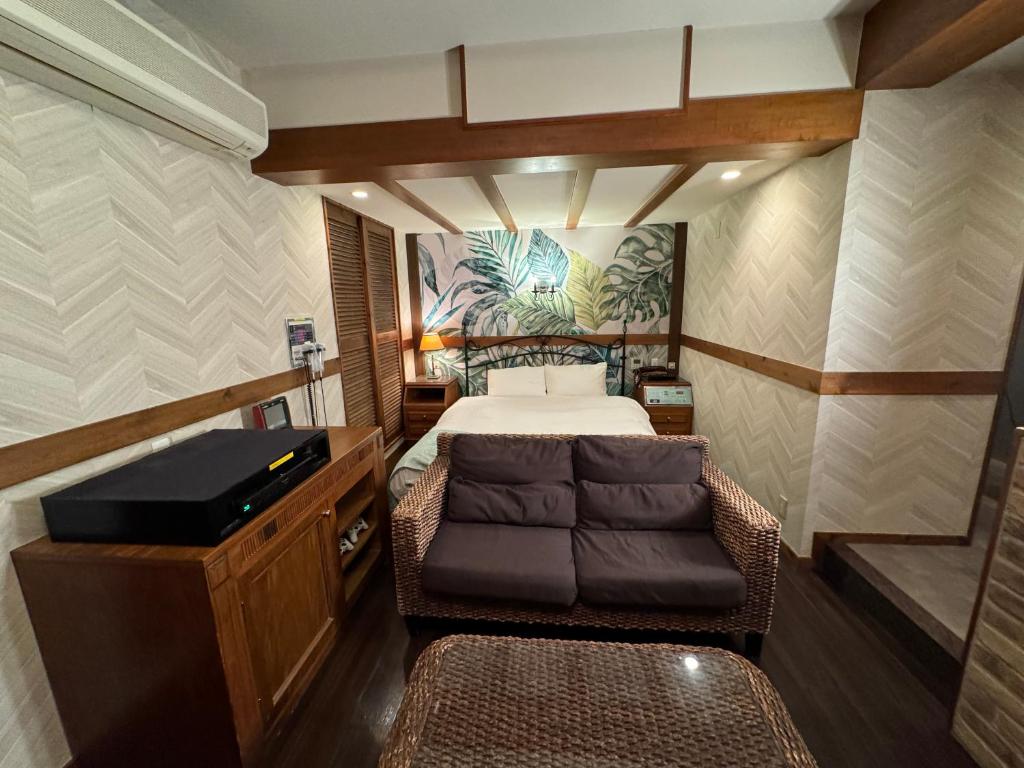 une petite chambre avec un lit et un canapé dans l'établissement LaLa Resort (Adult Only), à Kobe