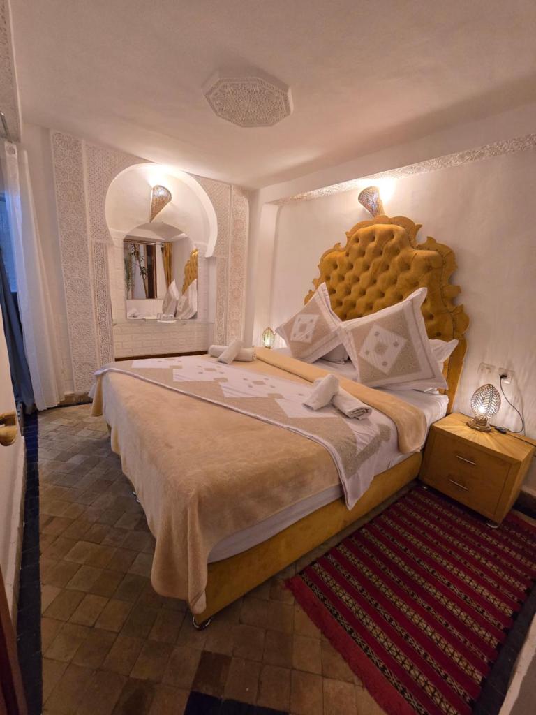 une chambre avec un grand lit avec une grande tête de lit dans l'établissement Riad Mounadim Fes, à Fès