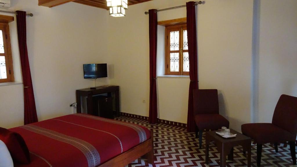 une chambre avec un lit, une télévision et une chaise dans l'établissement Riad Sabah, à Fès