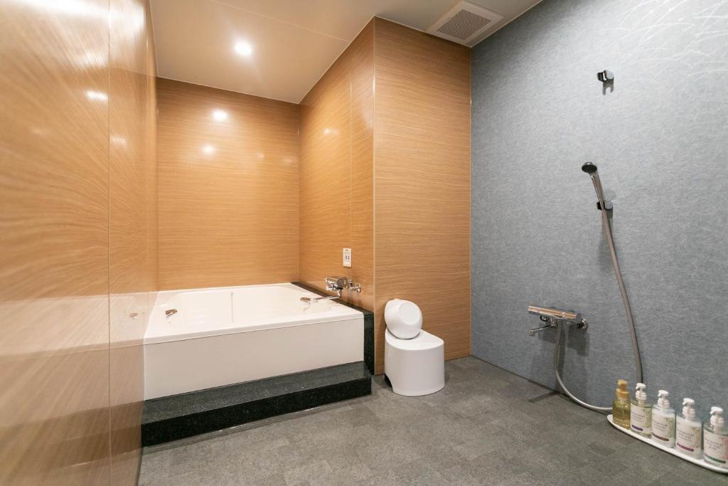 La salle de bains est pourvue d'une baignoire, d'une douche et de toilettes. dans l'établissement Hotel TEMARI Matsumoto, à Matsumoto