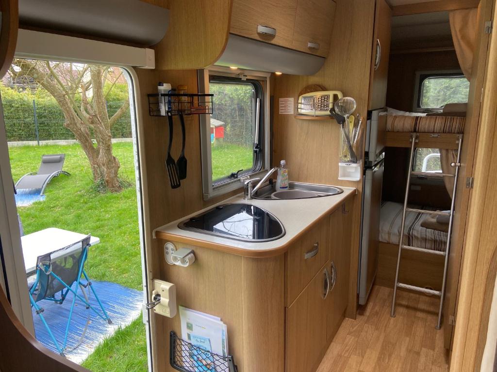 une cuisine dans un camping-car avec un évier dans l'établissement Camping-car au Charme de la Forêt Circuit des 25 Bosses, à Le Vaudoué