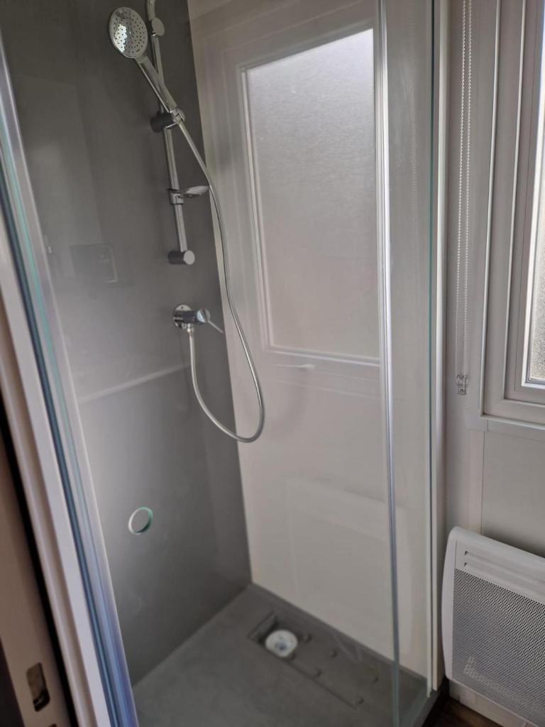 une douche avec une porte vitrée dans une salle de bain dans l'établissement Mobile home Bora bora, à Vias