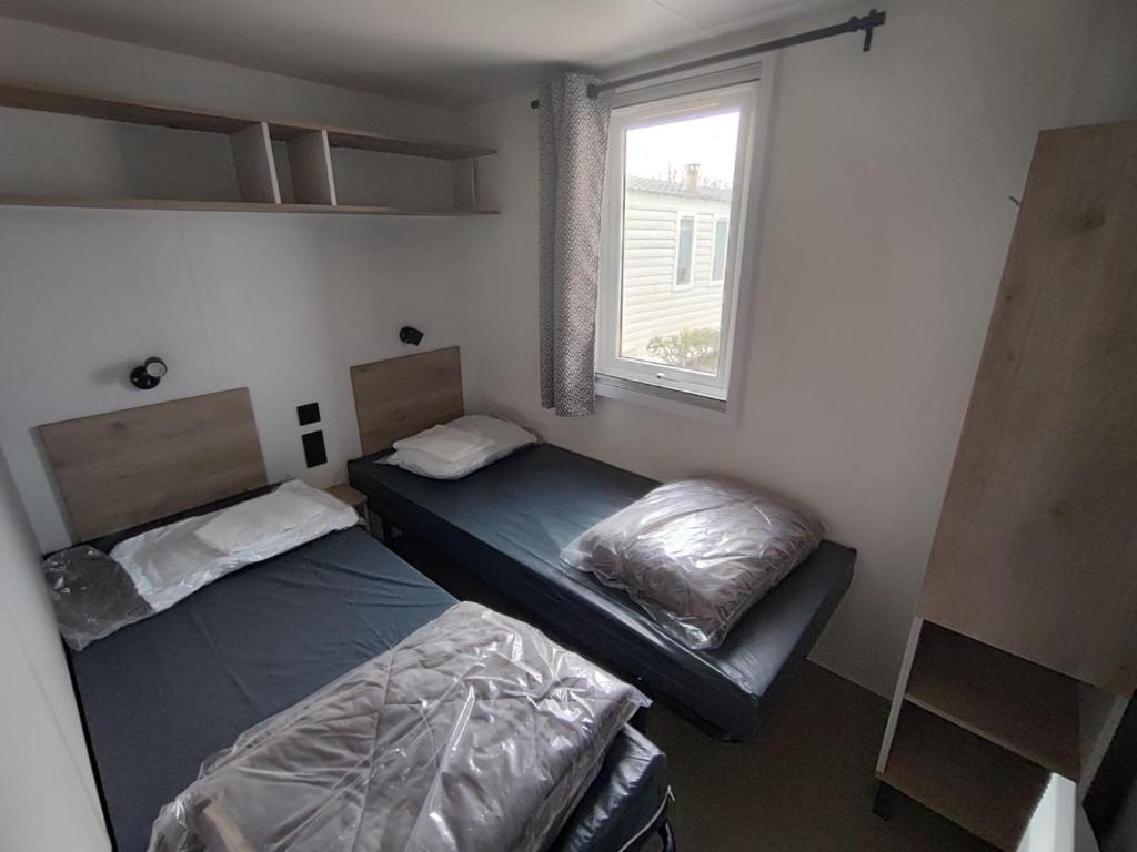 deux lits dans une chambre avec une fenêtre dans l'établissement Mobile-home tout confort 6 personnes climatisé, à Sète