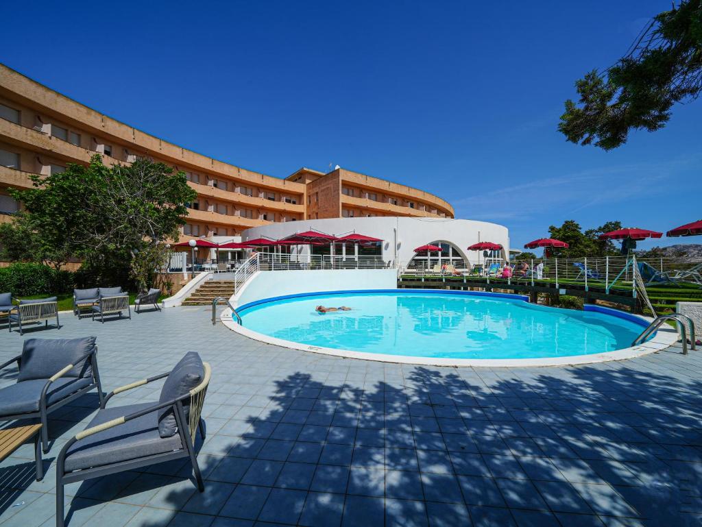une grande piscine devant un hôtel dans l'établissement Club Esse Roccaruja, à Stintino