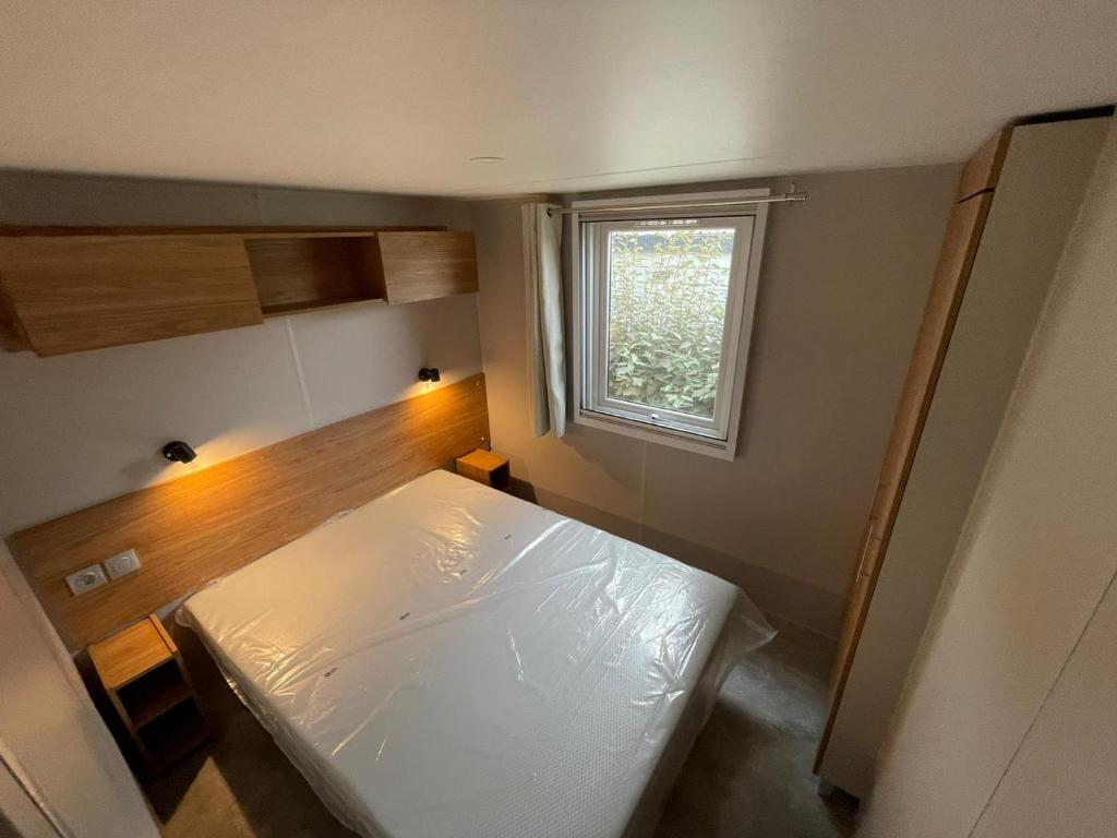 une petite chambre avec un lit blanc et une fenêtre dans l'établissement Mobilhome neuf à Camping Domaine l'Ile d'Or à Saint Raphaël, à Saint-Raphaël