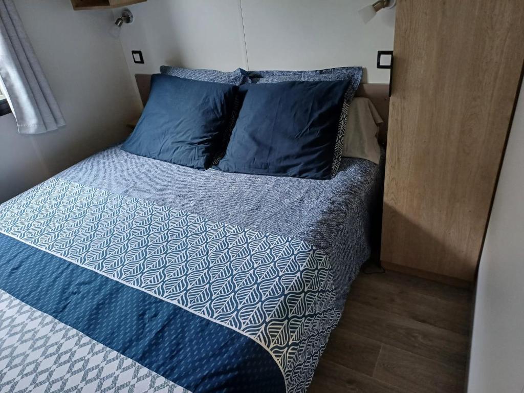 - un lit avec des oreillers bleus dans une petite pièce dans l'établissement Charmant mobil-home 178, à Narbonne