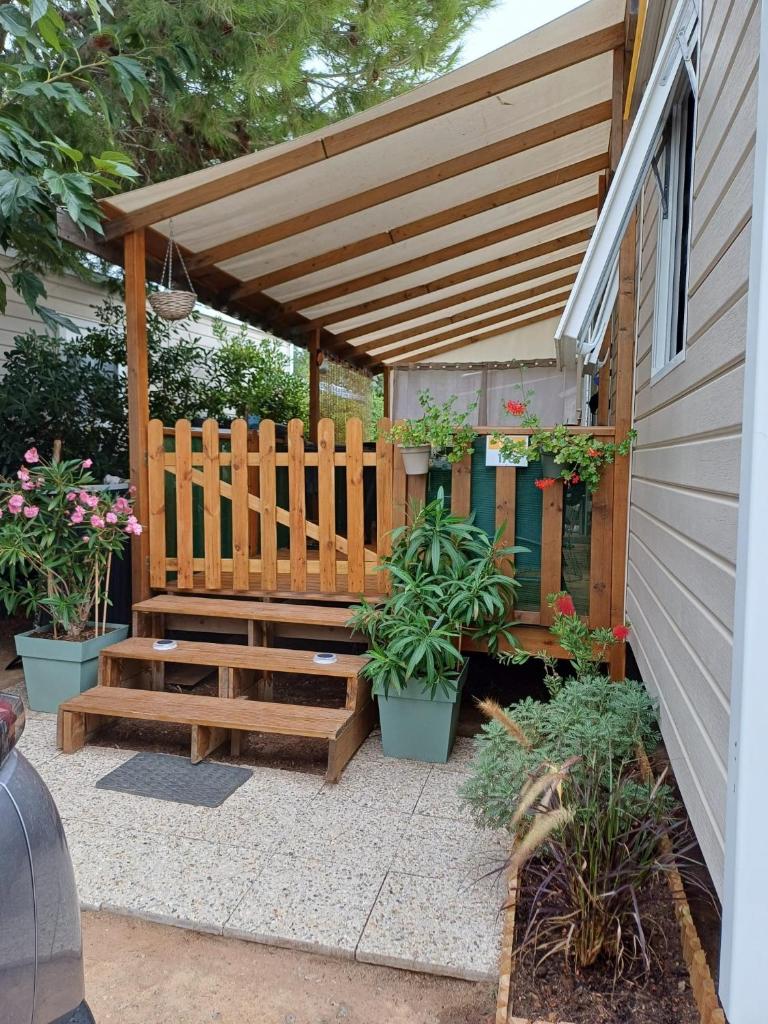 une pergola en bois avec un banc et quelques plantes dans l'établissement Charmant mobil-home 178, à Narbonne