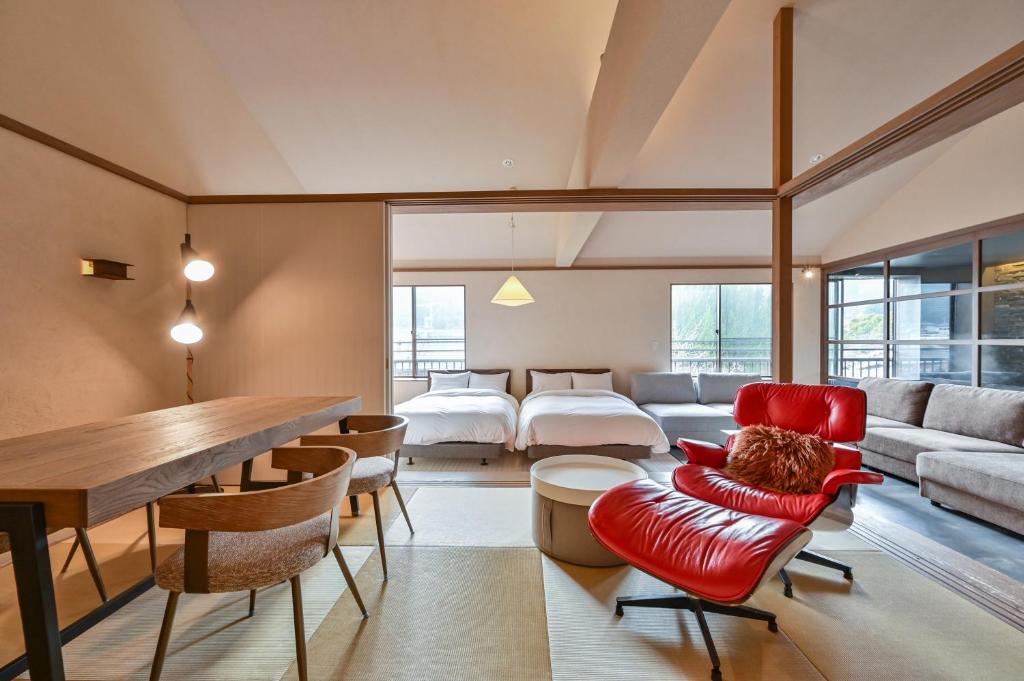 - un salon avec une chaise rouge et un lit dans l'établissement Ryokan Yoshidaya, à Ureshino
