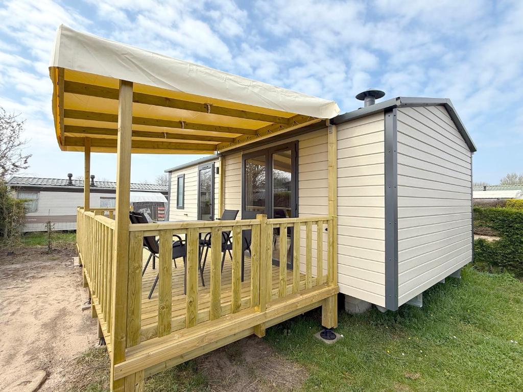 une petite maison avec une véranda et un auvent dans l'établissement MobilHome de la Coccinelle, à Gujan-Mestras