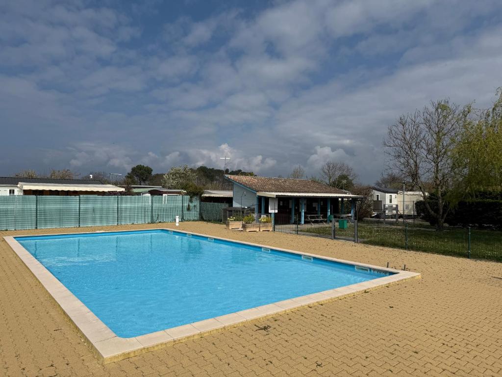 une grande piscine bleue devant une maison dans l'établissement MobilHome de la Coccinelle, à Gujan-Mestras