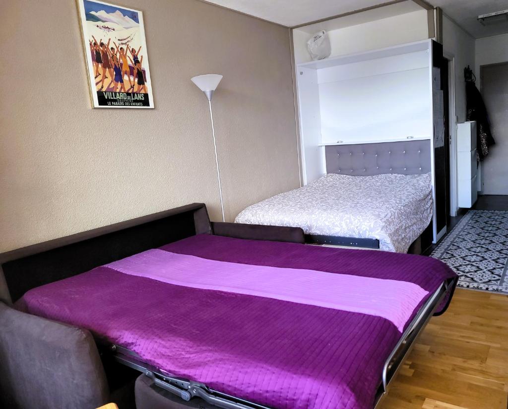 - une chambre avec 2 lits et une couverture violette dans l'établissement STUDIO plein sud "Les Arolles" Balcon de VILLARD DE LANS, à Villard-de-Lans 16 autres photos