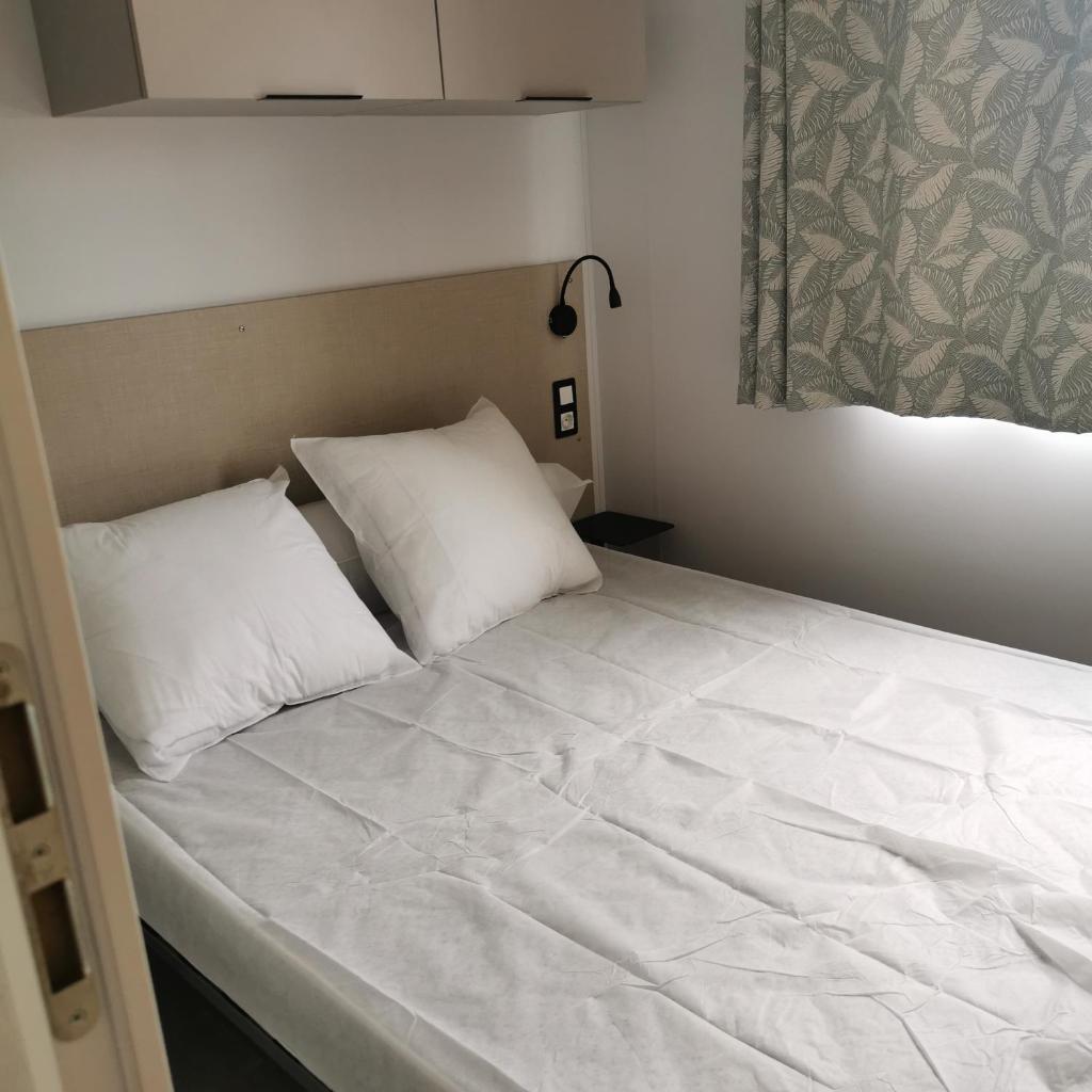 un lit avec des draps blancs et des oreillers dans une chambre dans l'établissement tony vacances, à Martigues