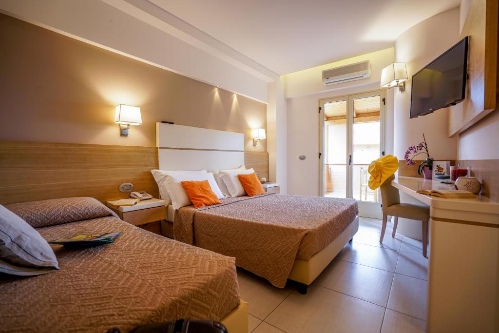 une chambre d'hôtel avec deux lits et une télévision dans l'établissement Hotel Villaggio Old River, à Capo Vaticano