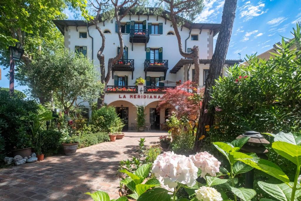 un bâtiment avec des fleurs devant lui dans l'établissement Hotel La Meridiana, sur le Lido de Venise