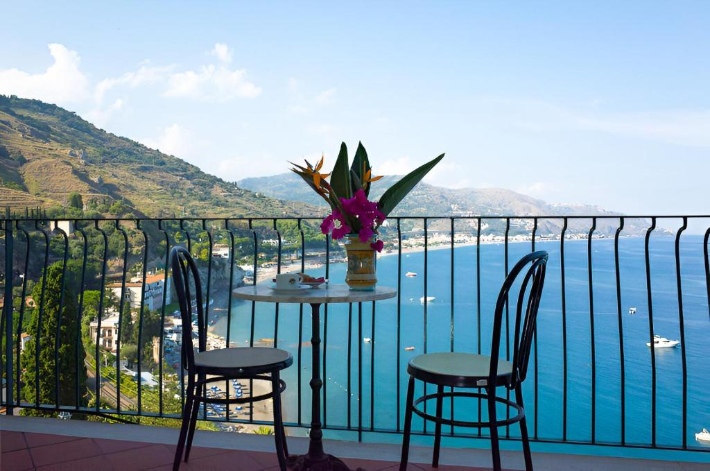 d'une table avec des chaises et un vase avec des fleurs sur le balcon. dans l'établissement HOTIDAY Taormina Mare, à Taormine