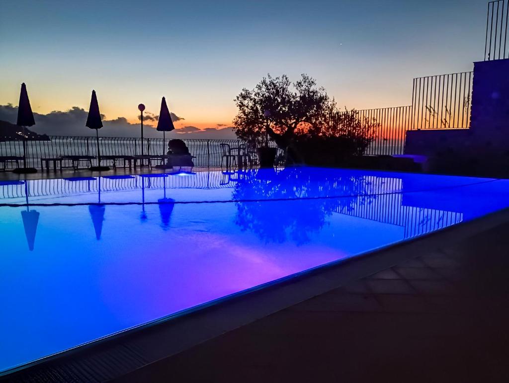 une piscine avec un éclairage bleu et violet au crépuscule dans l'établissement HOTIDAY Taormina Mare, à Taormine