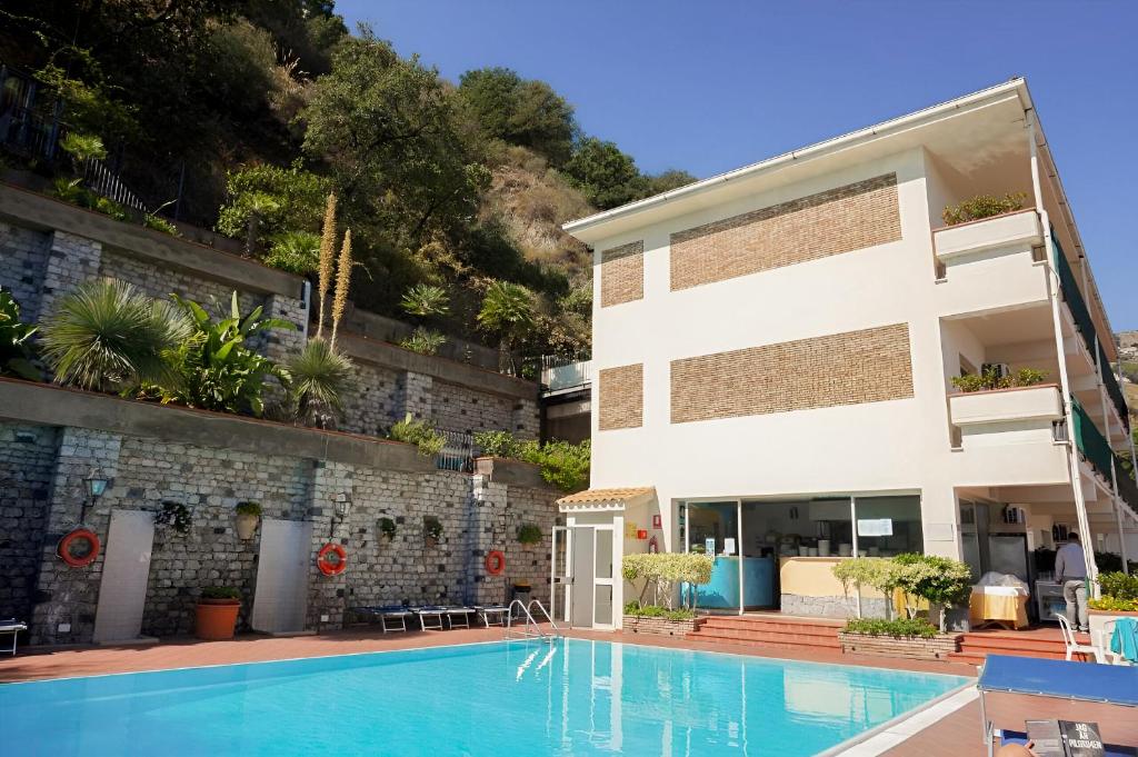 un hôtel avec une piscine devant un bâtiment dans l'établissement HOTIDAY Taormina Mare, à Taormine