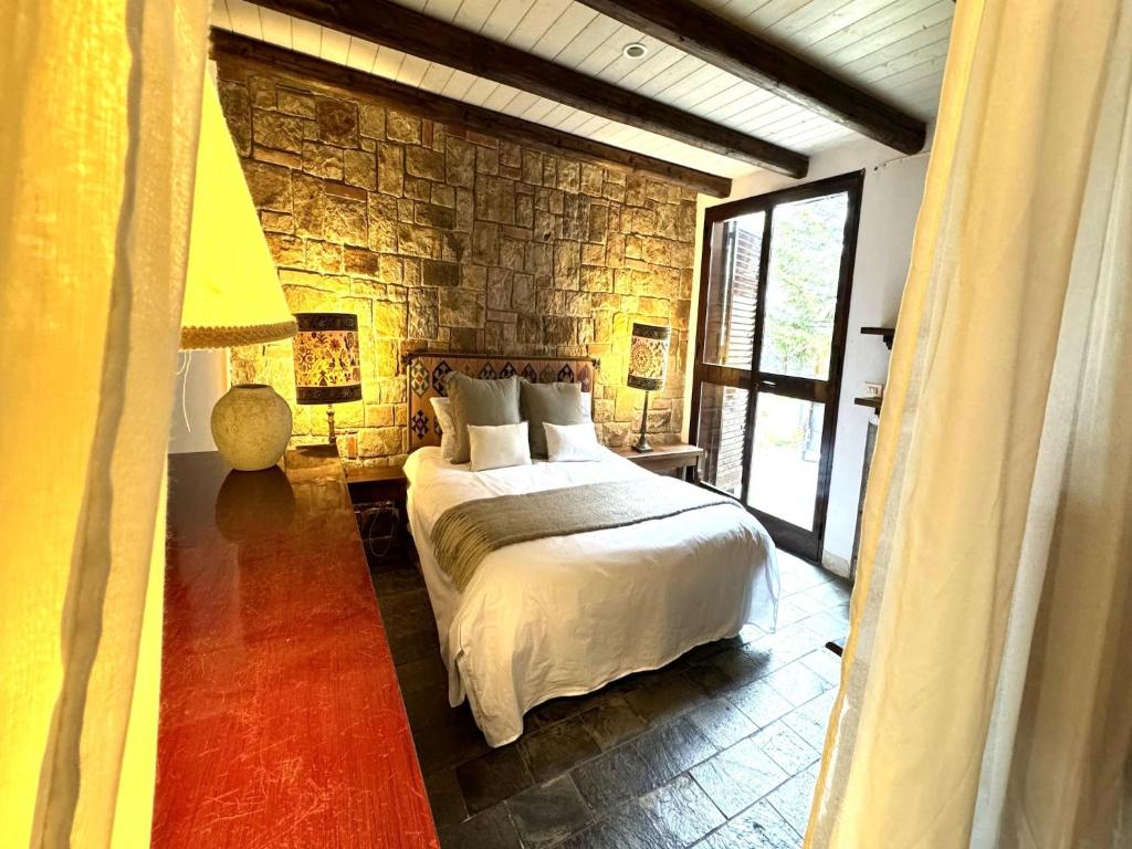 une chambre avec un lit et un mur en pierre dans l'établissement Villa in Cefalù with Pool and Forest Retreat, à Castelbuono