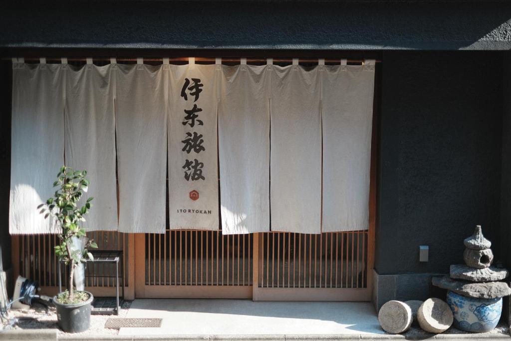 - un bâtiment avec des rideaux blancs et des écritures dans l'établissement Ito Ryokan, à Tokyo