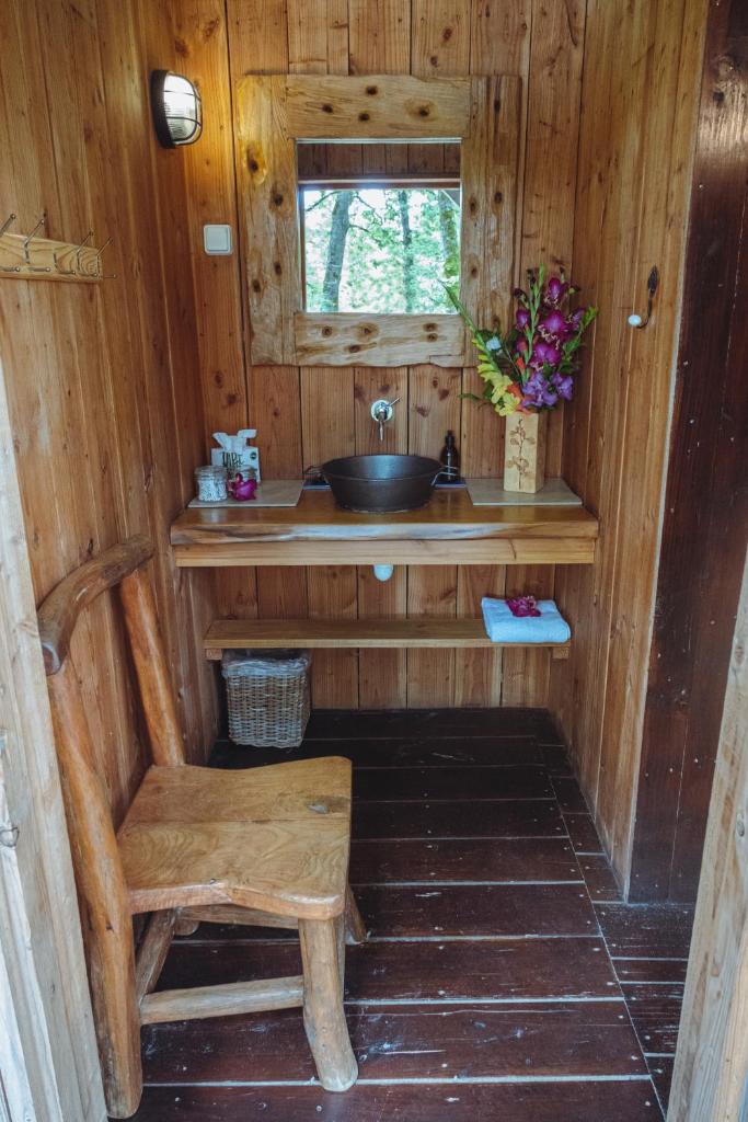La salle de bains en bois est pourvue d'un lavabo et d'une chaise en bois. dans l'établissement Le Camp, à Varen