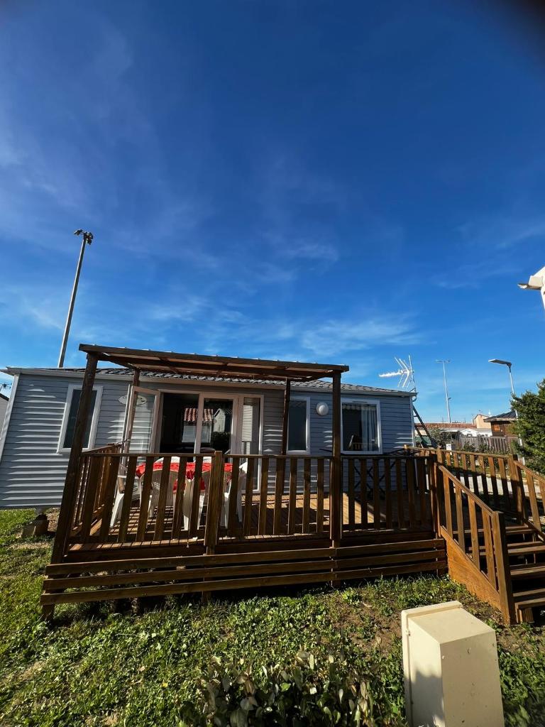 une maison avec une terrasse en bois et un toit dans l'établissement Mobil Home 014 climatisé -camping Novela-3Ch, à Port-la-Nouvelle